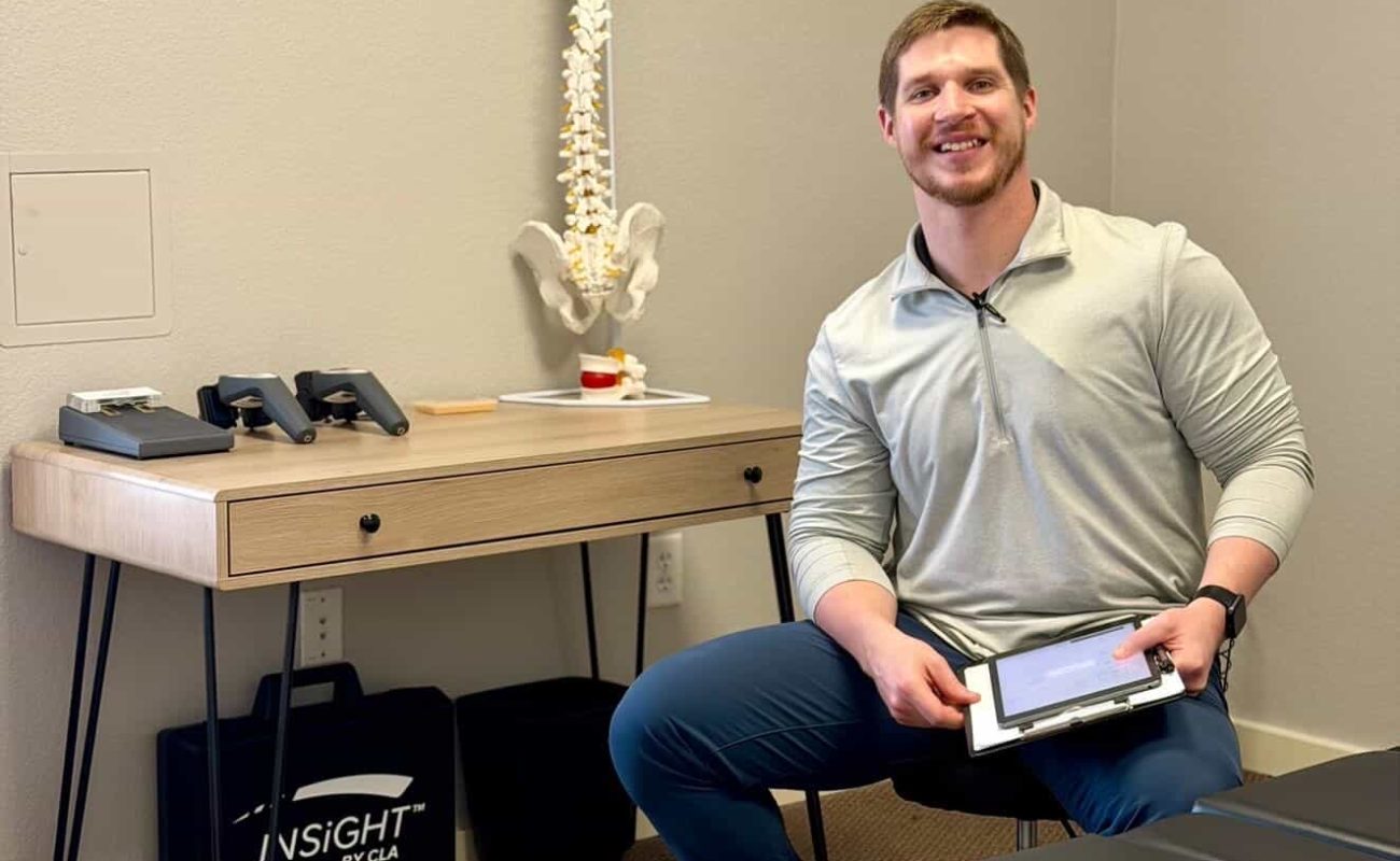 Dr. Cameron Williams standing beside a spine model in his Colleyville chiropractic office