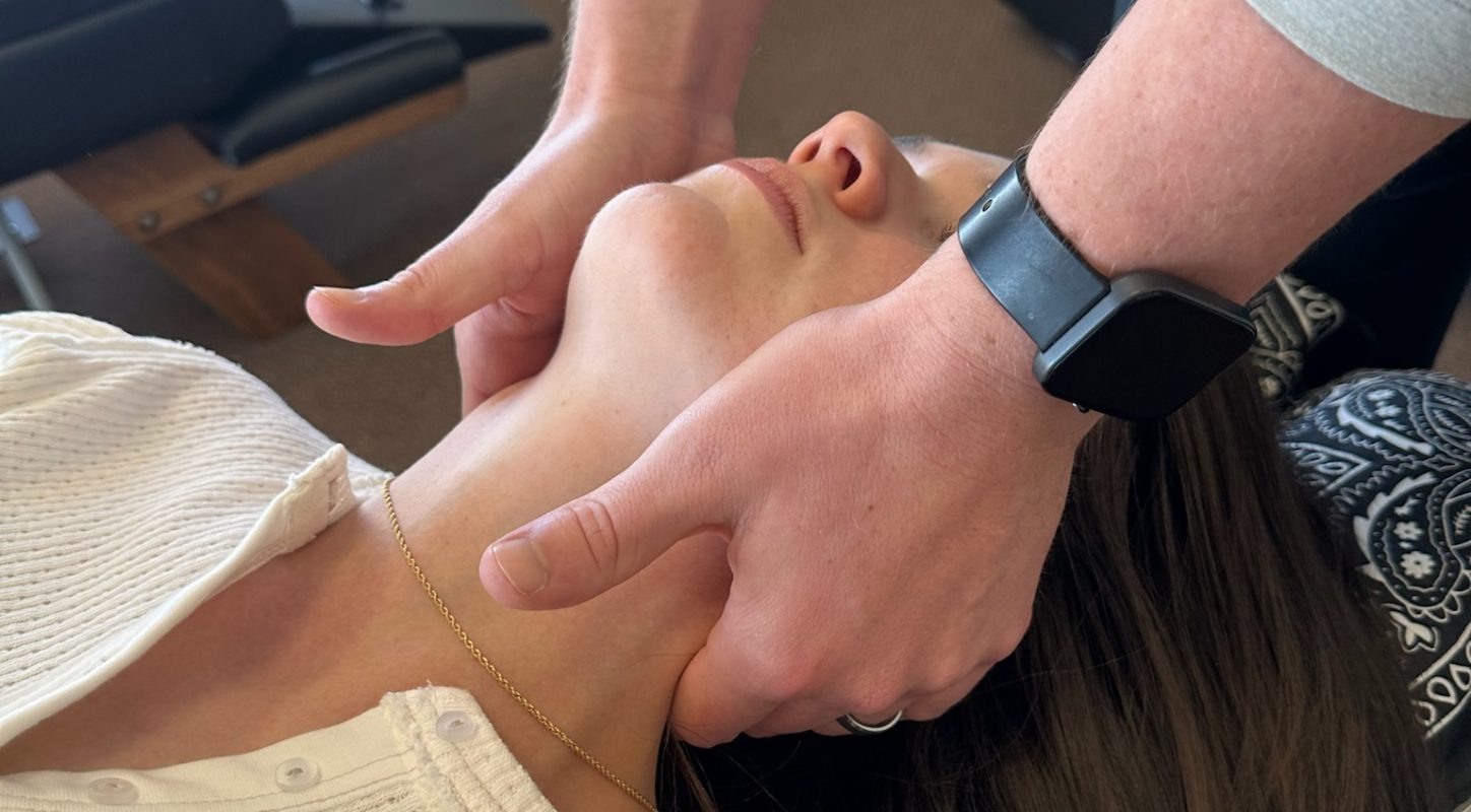 Close-up of a chiropractic adjustment on a patient's neck