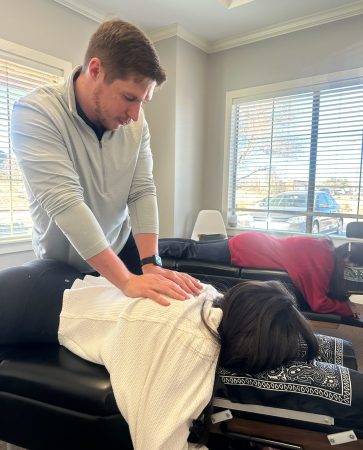 Dr. Cameron Williams adjusting a patient lying on a treatment table by a window