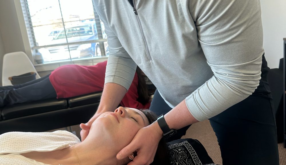 Dr. Cameron Williams performing a hands-on neck and shoulder adjustment on a patient