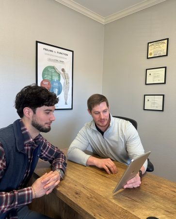 Consultation at a desk with a laptop at Radiant Chiropractic