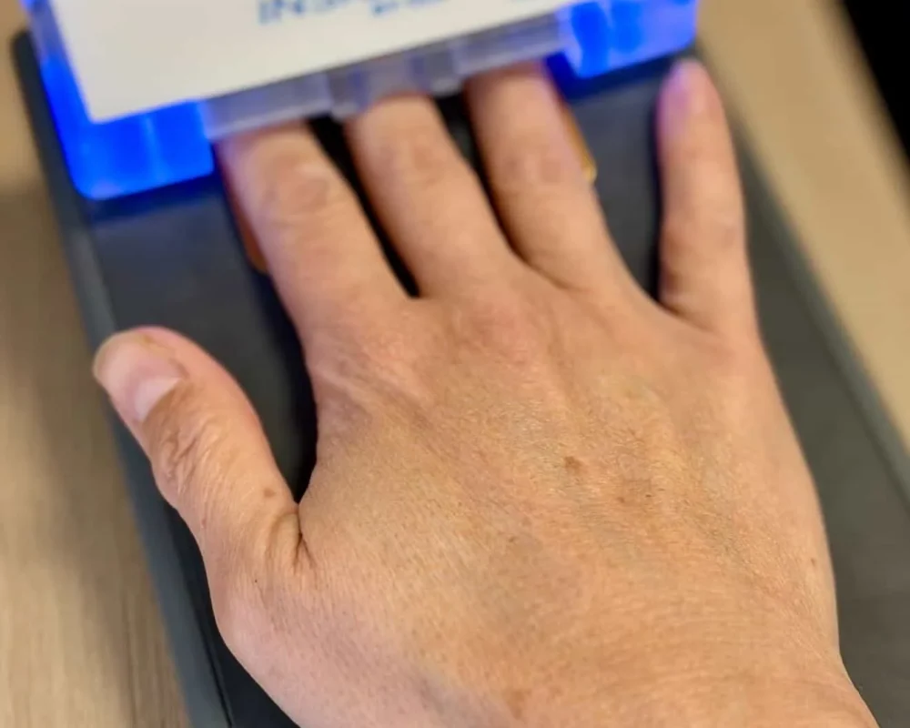 Hand placed on an illuminated CLA INSiGHT scanning device for a nervous system assessment.