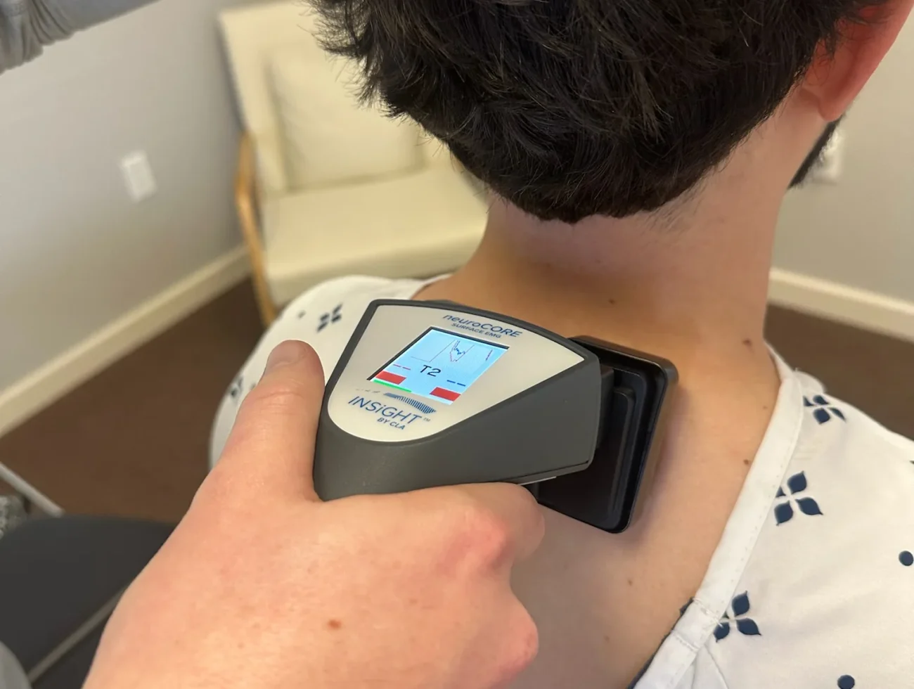 Chiropractor performing a CLA INSiGHT nervous system scan on a patient's upper back.