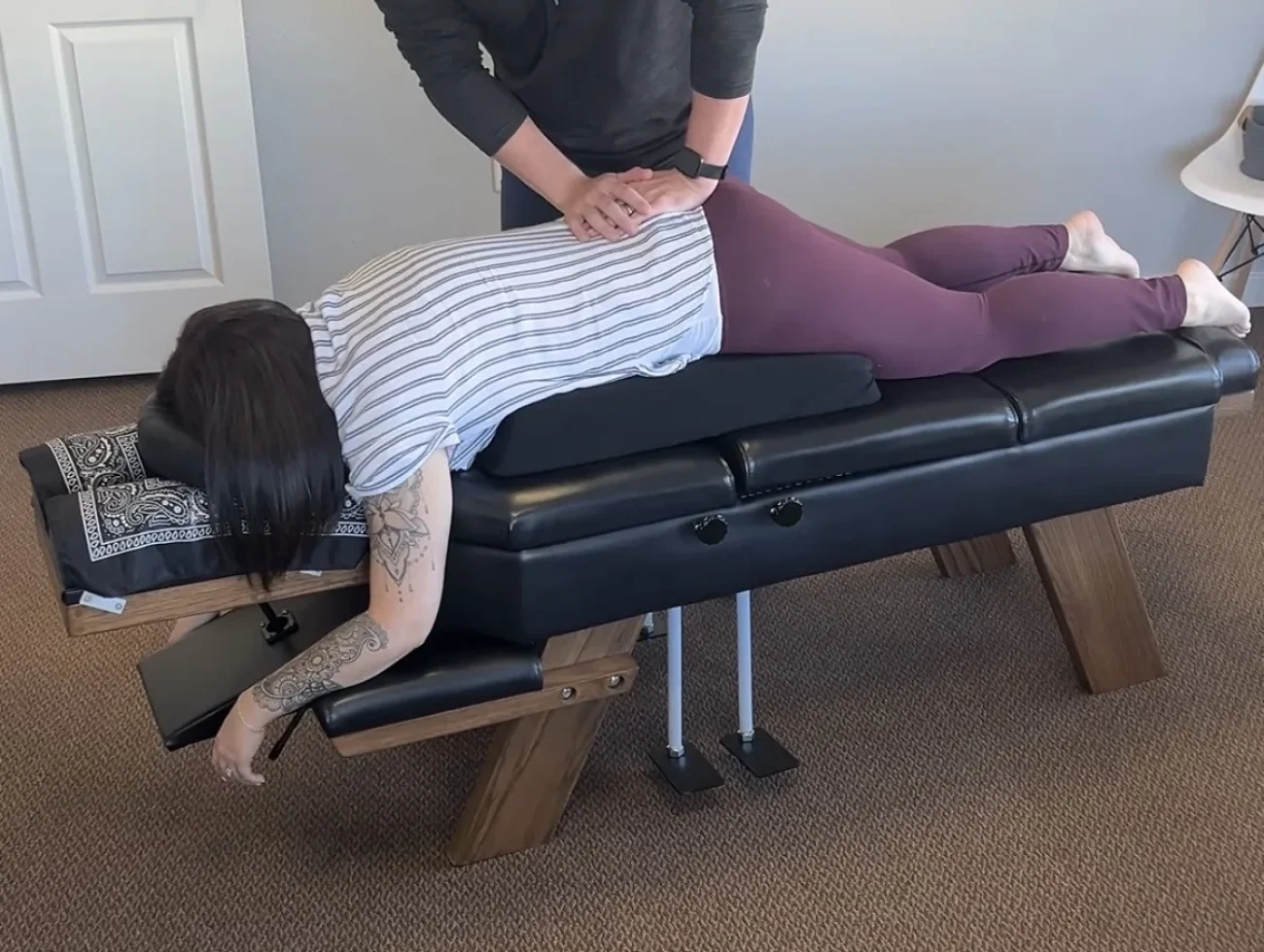 Dr. Cameron Williams adjusts a patient resting prone on a pregnancy support cushion on an adjustment table.