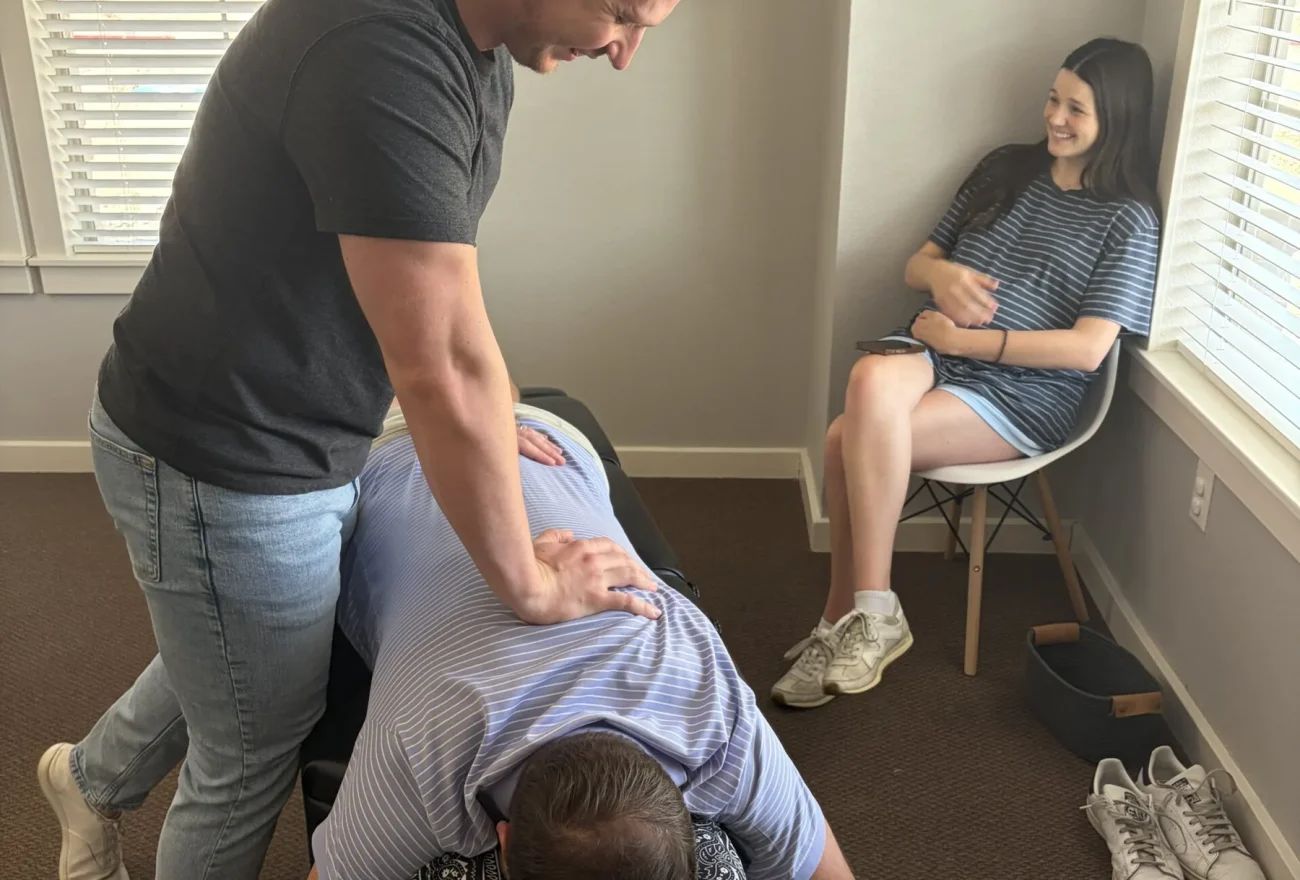 Dr. Cameron Williams performs a chiropractic back adjustment on a patient lying prone on an adjusting table.