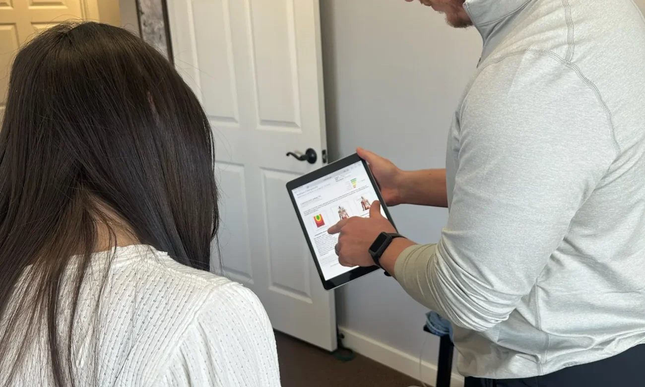 Dr. Cameron Williams shows scan results on a tablet to a seated patient during an office consultation.