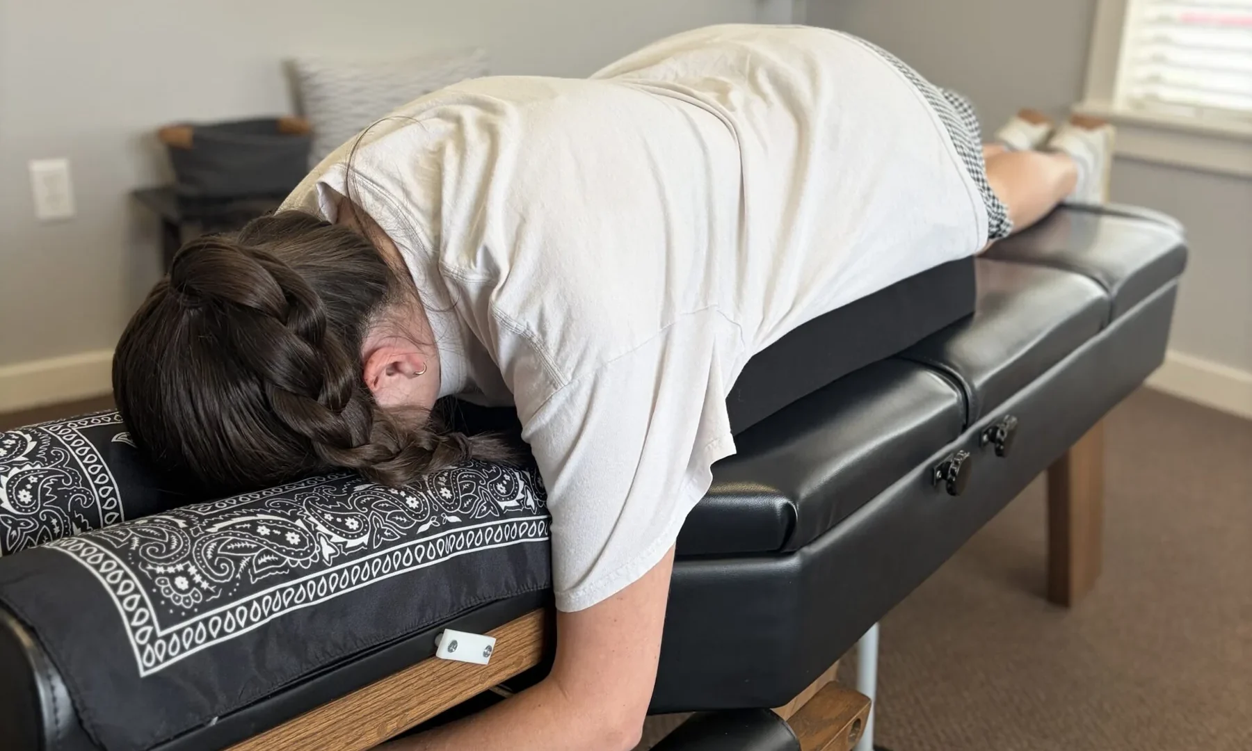 Woman lying face down on a chiropractic adjusting table supported by a specialized pregnancy pillow.